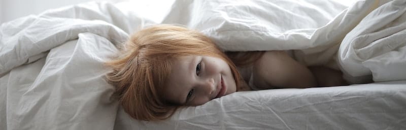 child in bed smiling